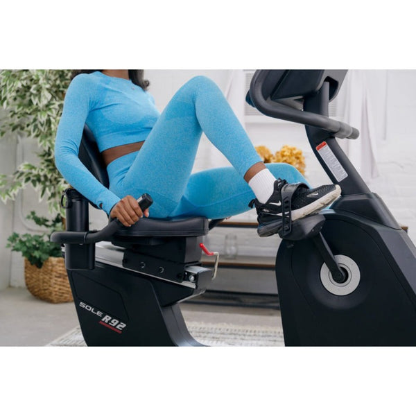 Fit woman stretching in blue workout attire next to exercise bike in a modern home gym