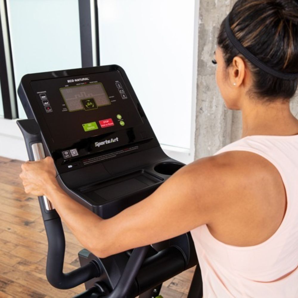 Woman using SportArt elliptical machine in modern gym setting for effective cardio workout