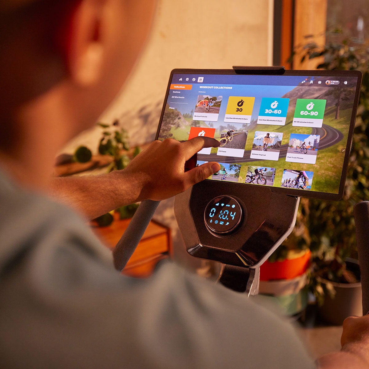 User interacts with a smart treadmill's touchscreen display for fitness programs.