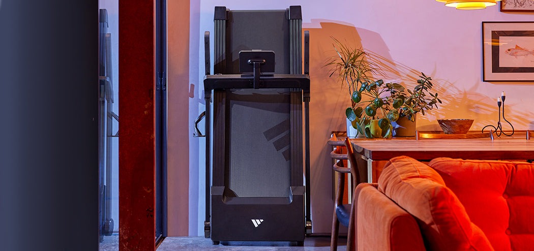 Adidas T24c Folding Treadmill compactly folded against a wall, highlighting its space-saving design.