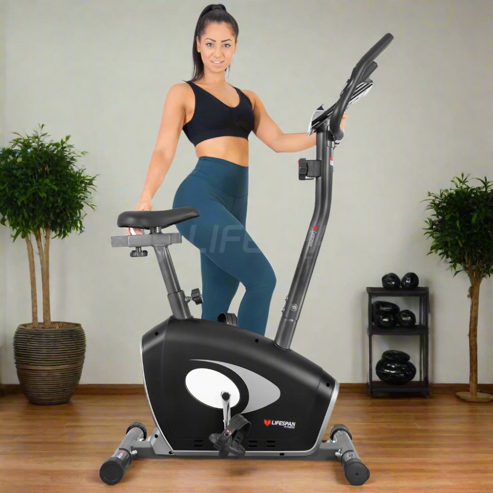 Lifespan Fitness EXER-58 Exercise Bike featuring a woman in workout attire, demonstrating a stationary cycling workout in a modern home setting, designed for low-impact cardio and fitness training.