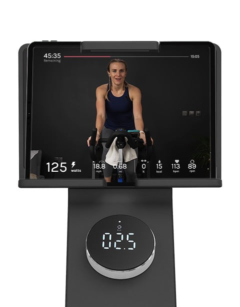 Close-up of Lifespan Fitness SM720i Spin Bike control panel, featuring a user adjusting settings on a sleek digital display for incline and decline workouts.