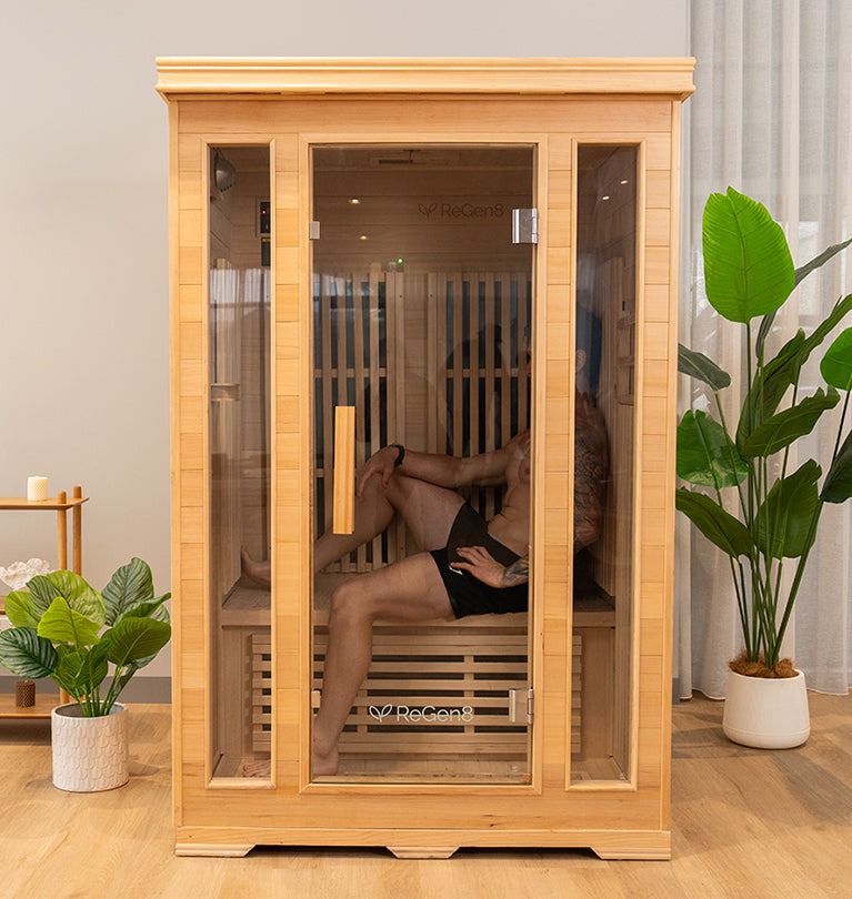 Modern wooden sauna with a woman preparing to enter, featuring lush green plants in a stylish indoor setting.