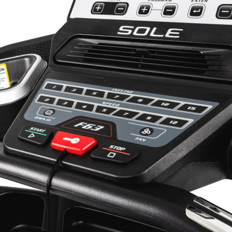 Treadmill control panel with a hand pressing the enter button for program selection.