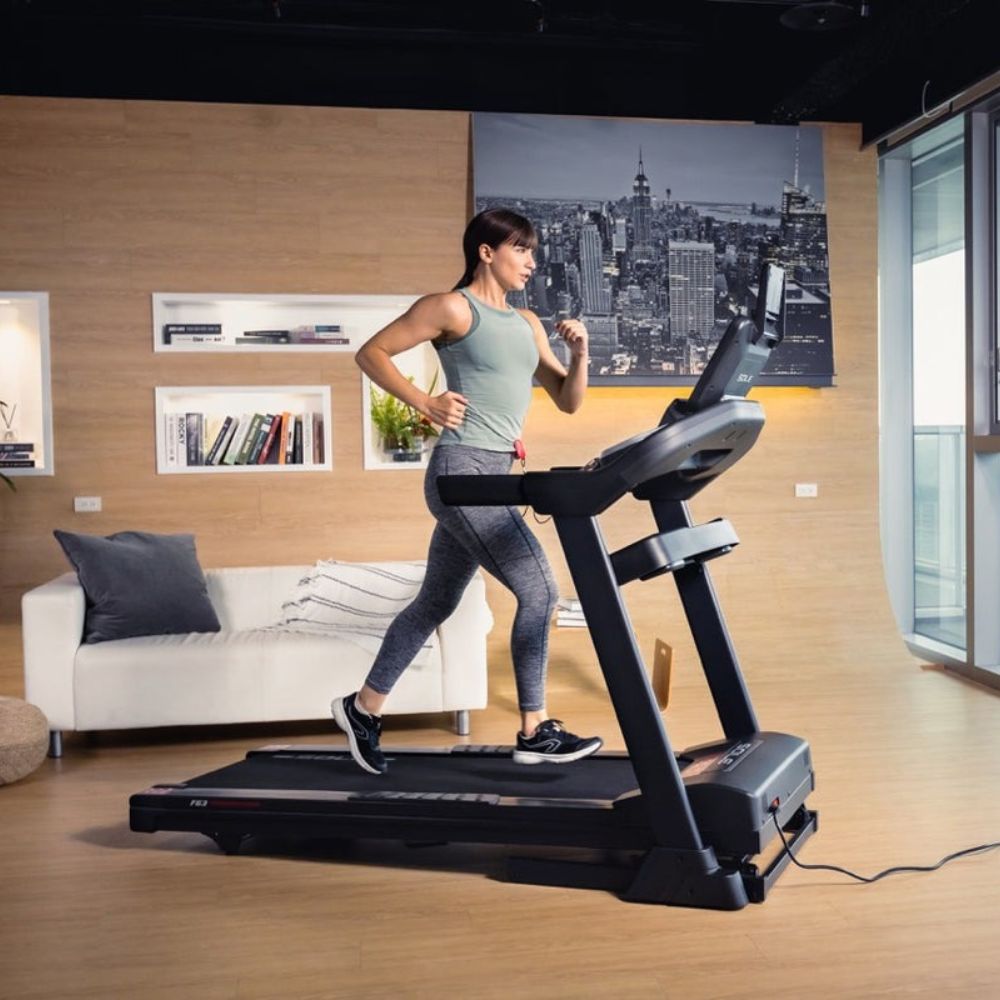 Woman exercising on treadmill in modern apartment with city view