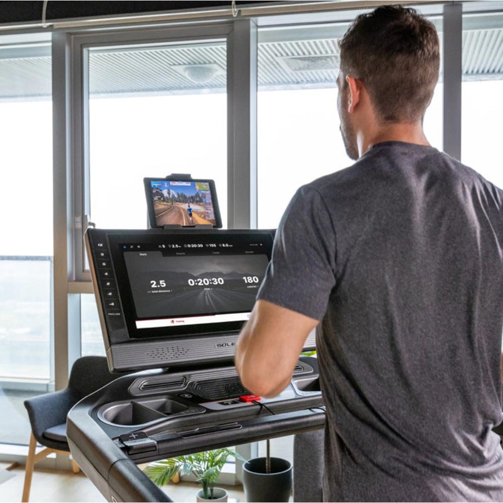 User interacting with SOLE fitness tablet displaying workout stats and classes