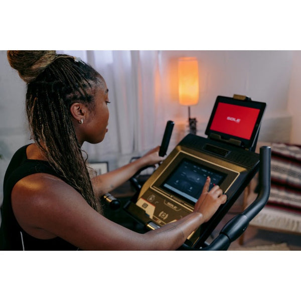 Woman exercising on a Sole elliptical machine with a joyful expression