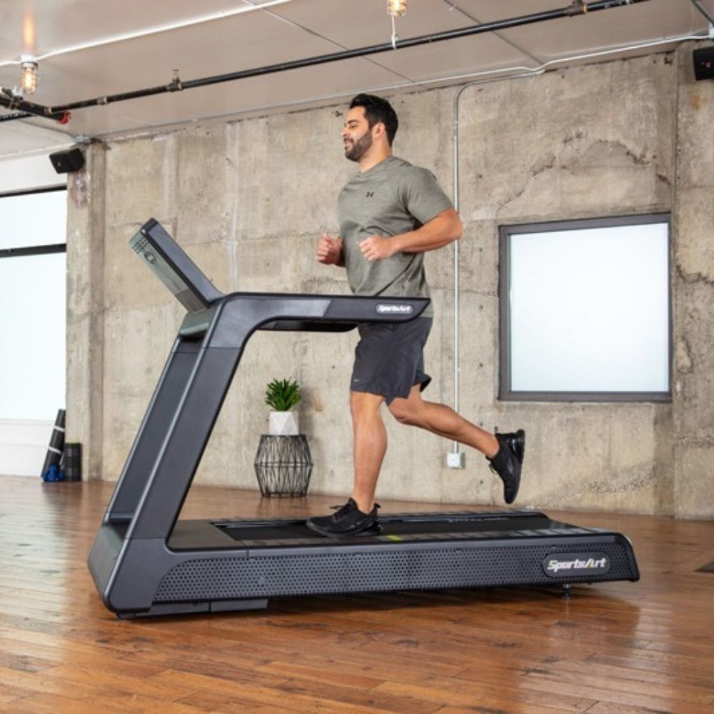 Woman jogging on a SportsArt treadmill in a modern gym setting