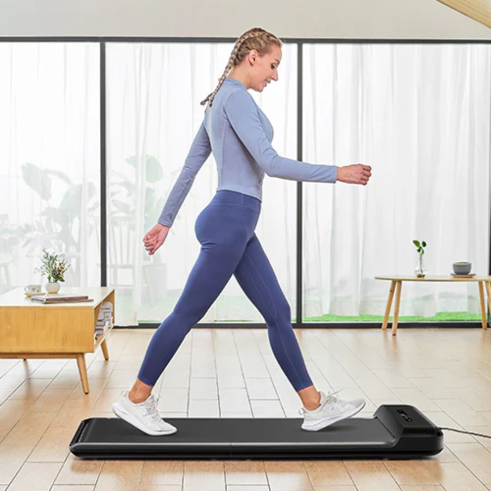 Woman exercising on a compact treadmill in a modern home with natural lighting